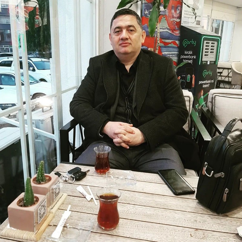 Koray Çokol bir kafede, önünde iki bardak çayla otururken