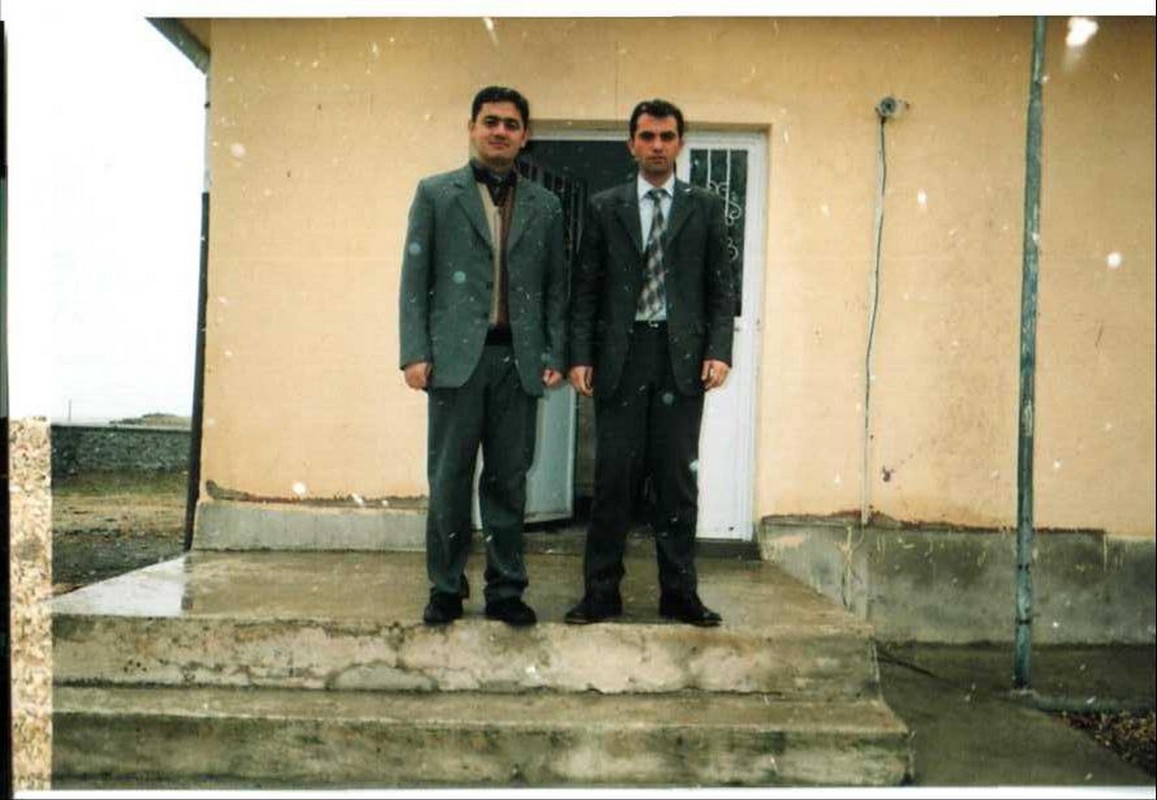 Genç Koray Çokol ve bir meslektaşı, bir köy okulunun giriş merdiveninde